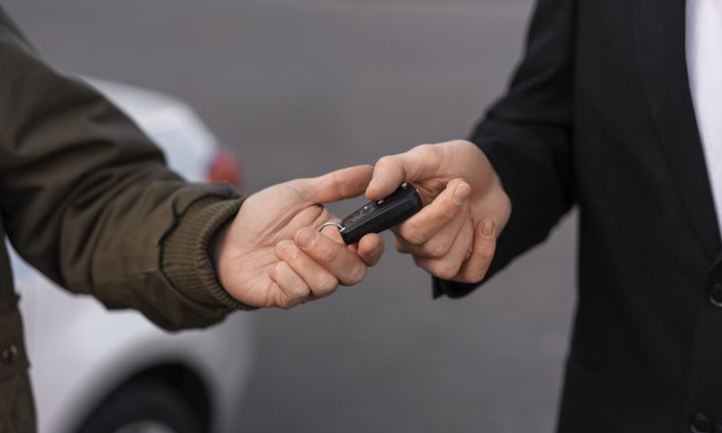 A man giving the car key to the another person.